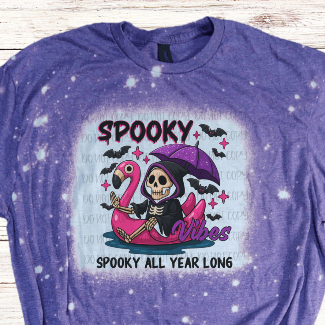 Purple t-shirt with a Halloween-themed design featuring on flamingo water tube and skeleton
